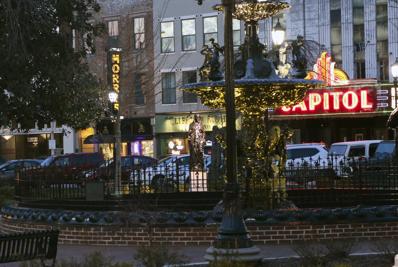 The fountain in Fountain Square Park, with the Capitol marquee and storefronts behind it, in downtown Bowling Green.