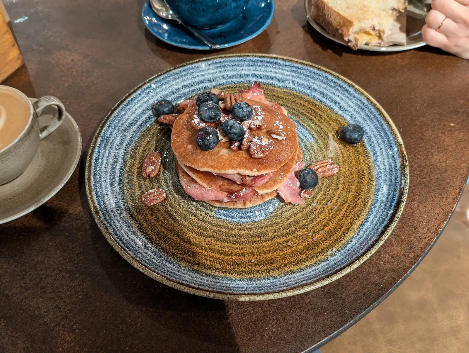 Bacon and maple pancakes with blueberries and pecans, served with coffee