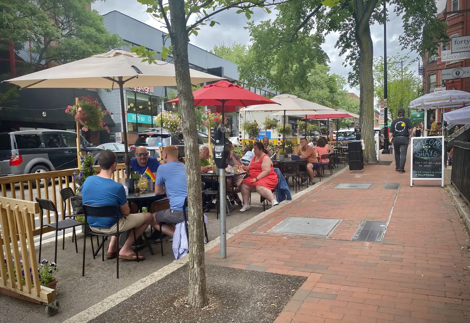 Diners at umbrella-shaded tables on a sidewalk patio in Cambridge, Massachusetts