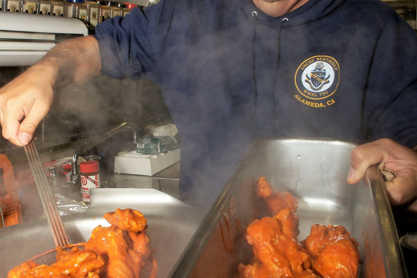 Buffalo chicken wings tossed in sauce in the galley of the U.S. Coast Guard cutter Bertholf